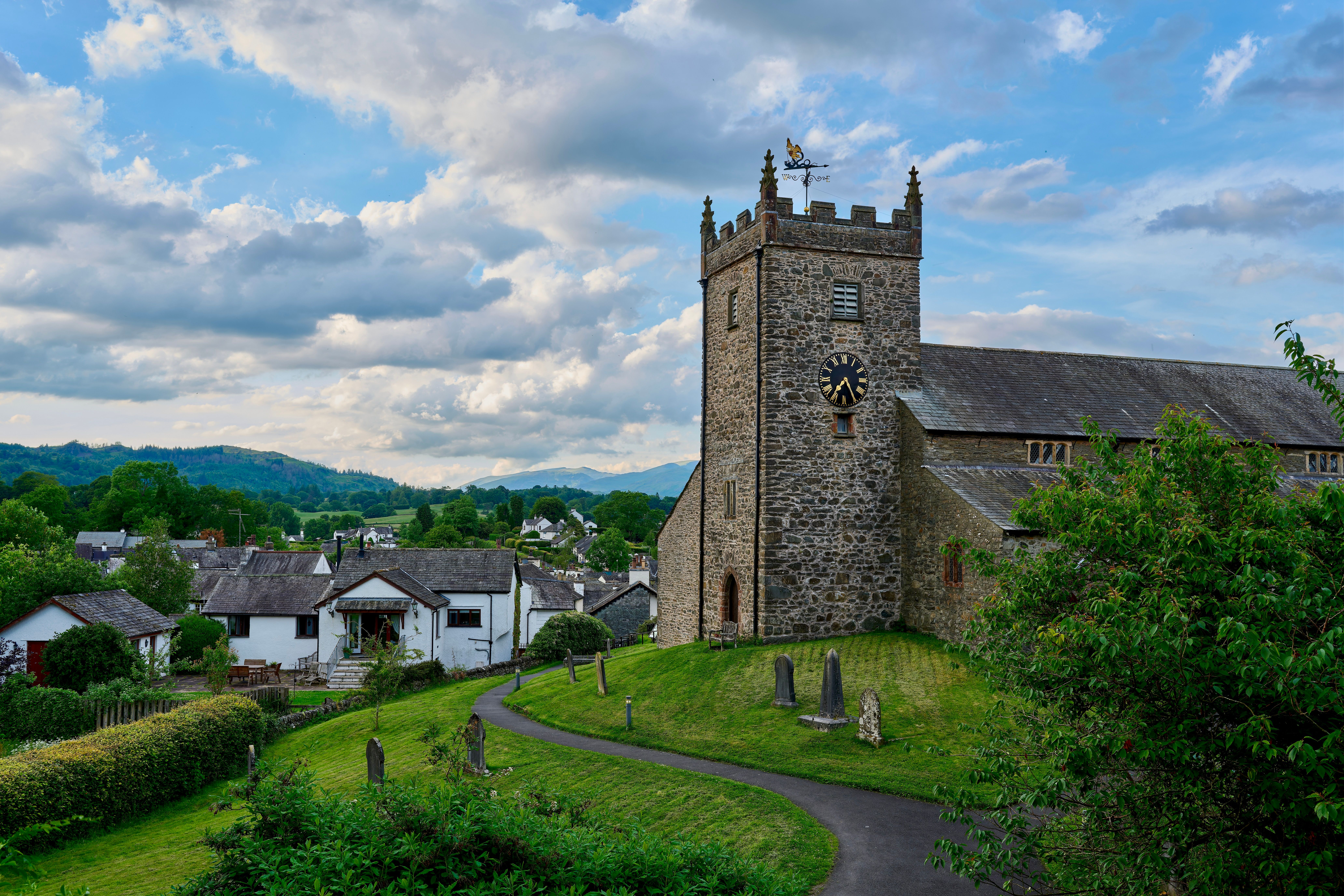 Charming stone church with clock tower in the tranquil Lake District, England. Ideal travel destination for nature and architecture lovers.