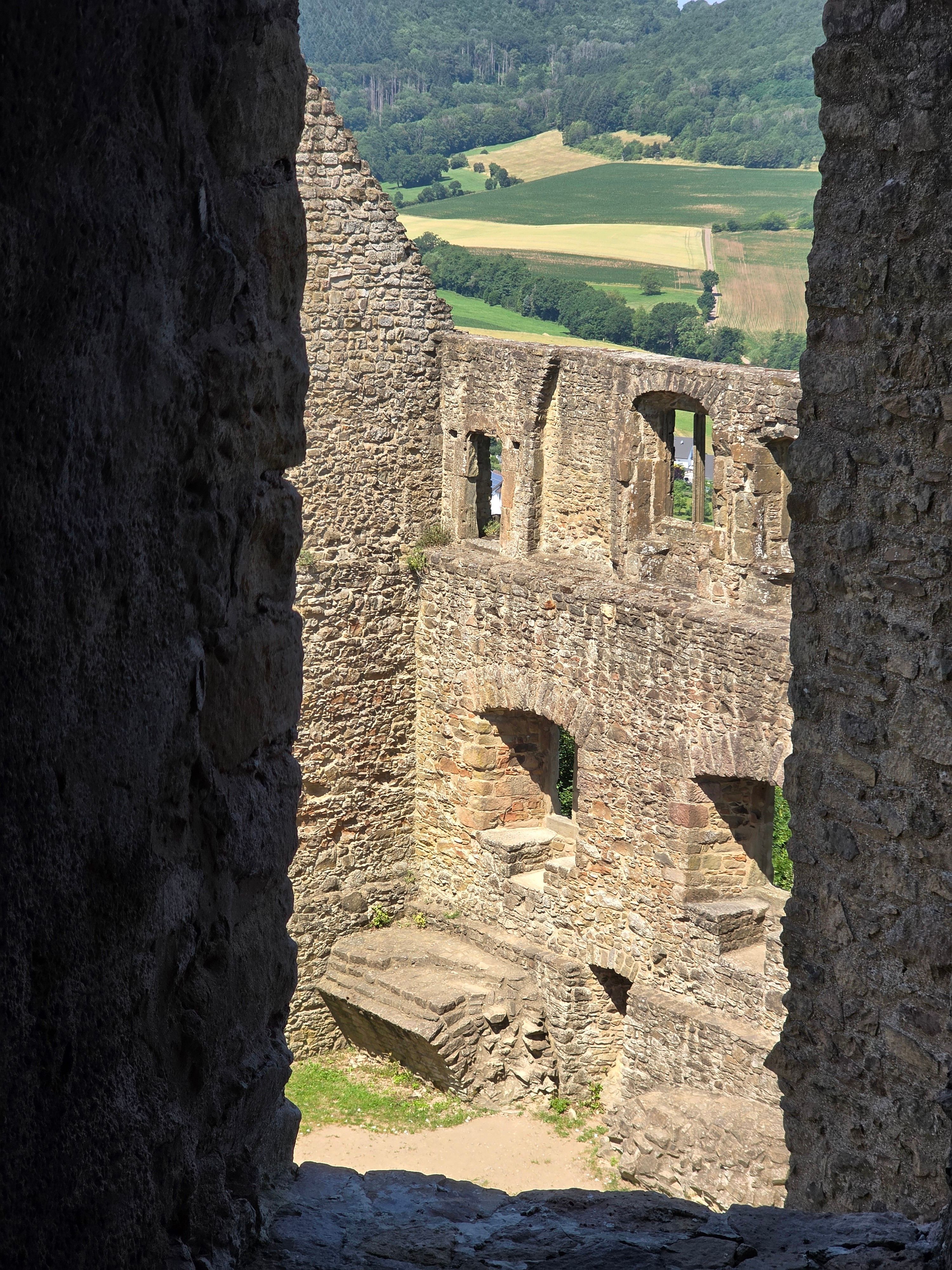 View from ancient ruins overlooking lush green countryside under a clear blue sky.