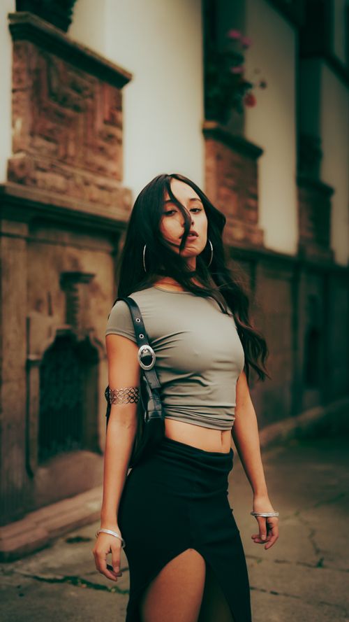 Free Fashionable woman walking confidently outside an old building, showcasing modern style. Stock Photo