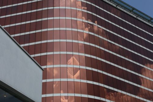 Free Red glass building reflecting cloudy sky on its facade. Stock Photo