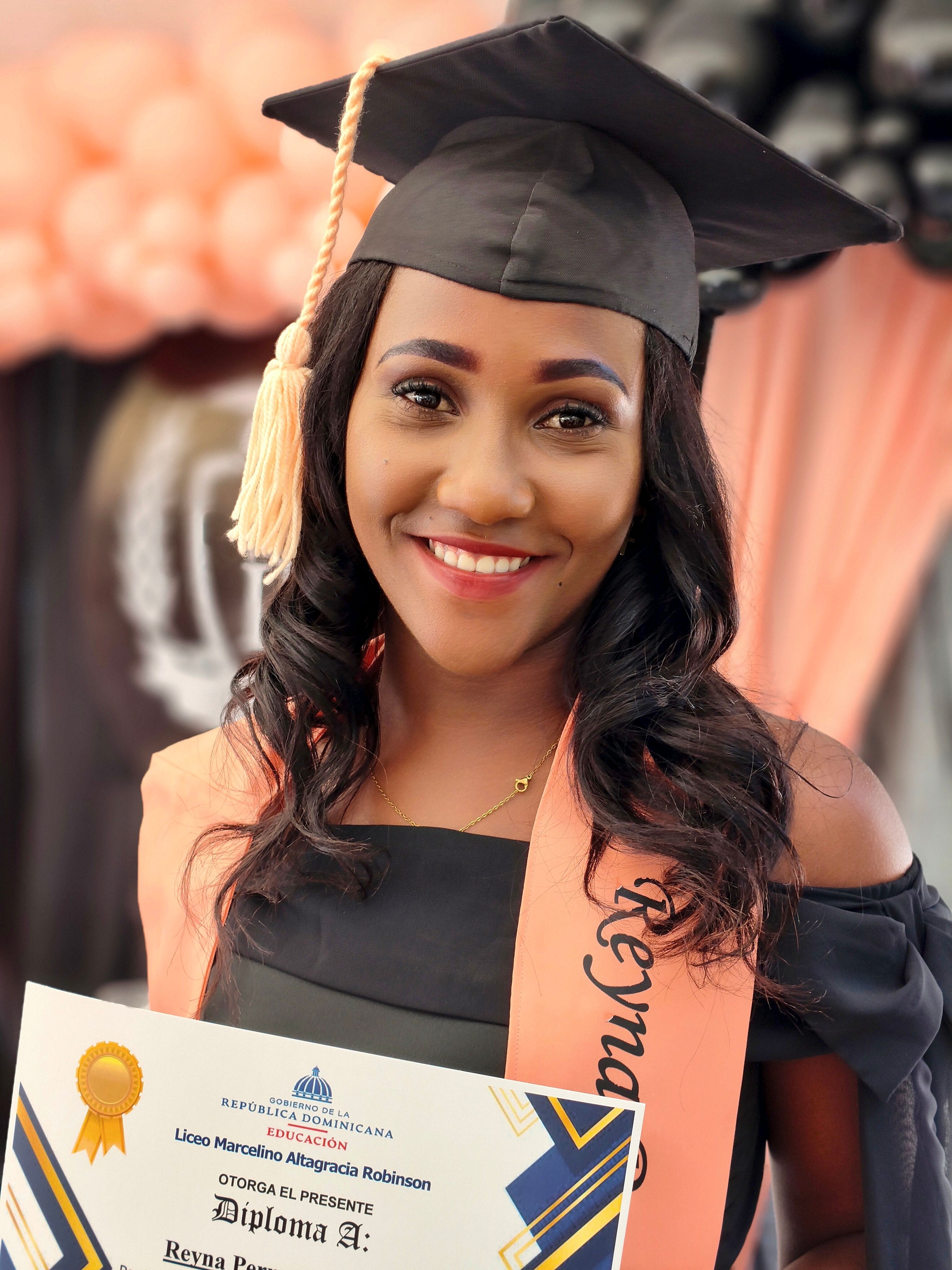 A graduate with cap and gown smiles while holding a diploma, celebrating her achievement.