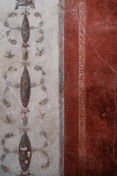 Historic Roman fresco with intricate designs and red tone from an archaeological site.