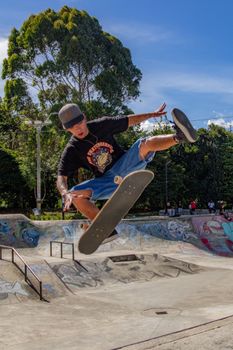 Energetic skateboarder executing a mid-air trick under a clear blue sky in an urban skate park.. pexels, energetic, skateboar
