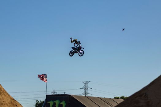 Motorcyclist performs an aerial stunt with a clear blue sky backdrop.