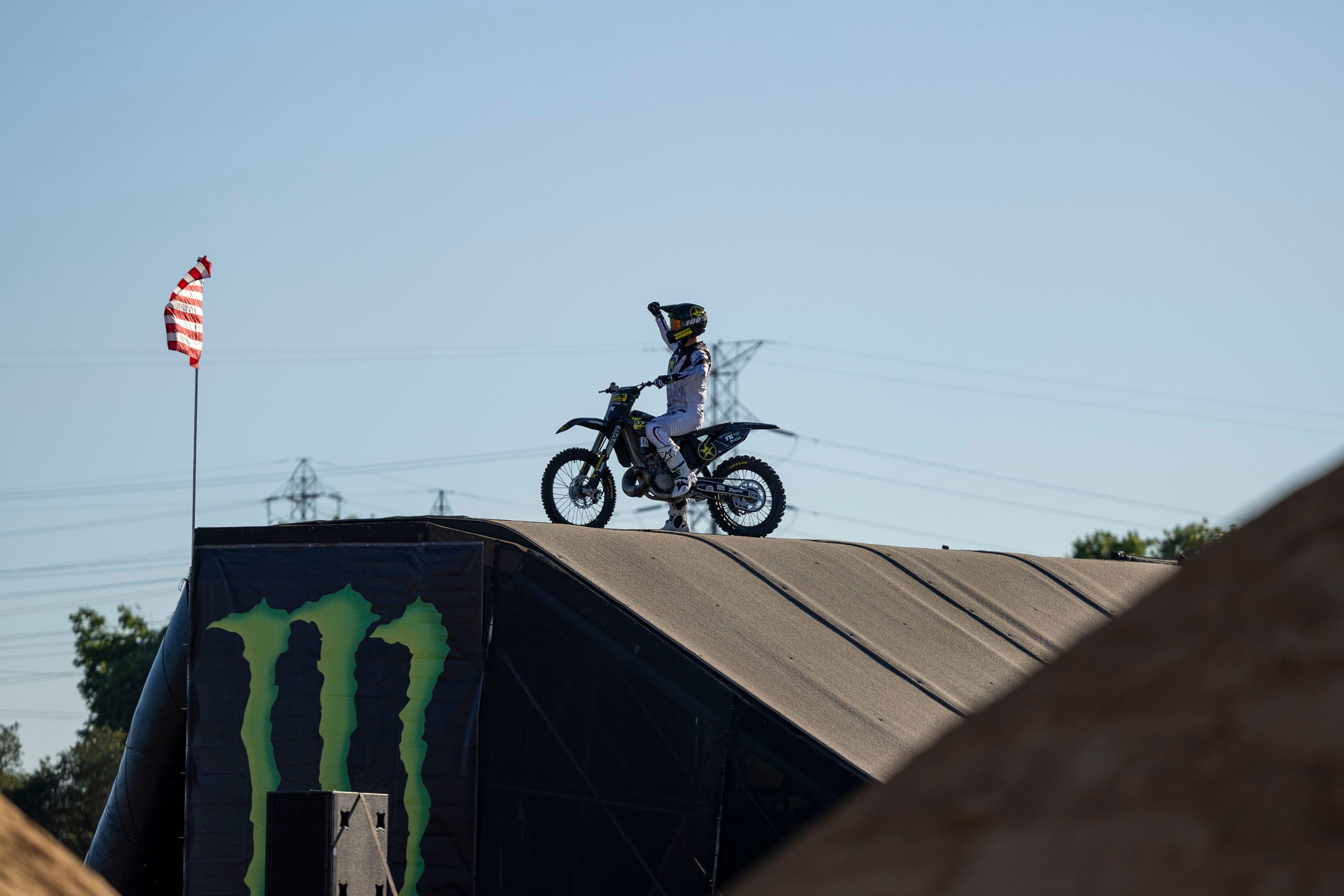 Motocross rider performing a stunt on a large ramp during a sunny day event.