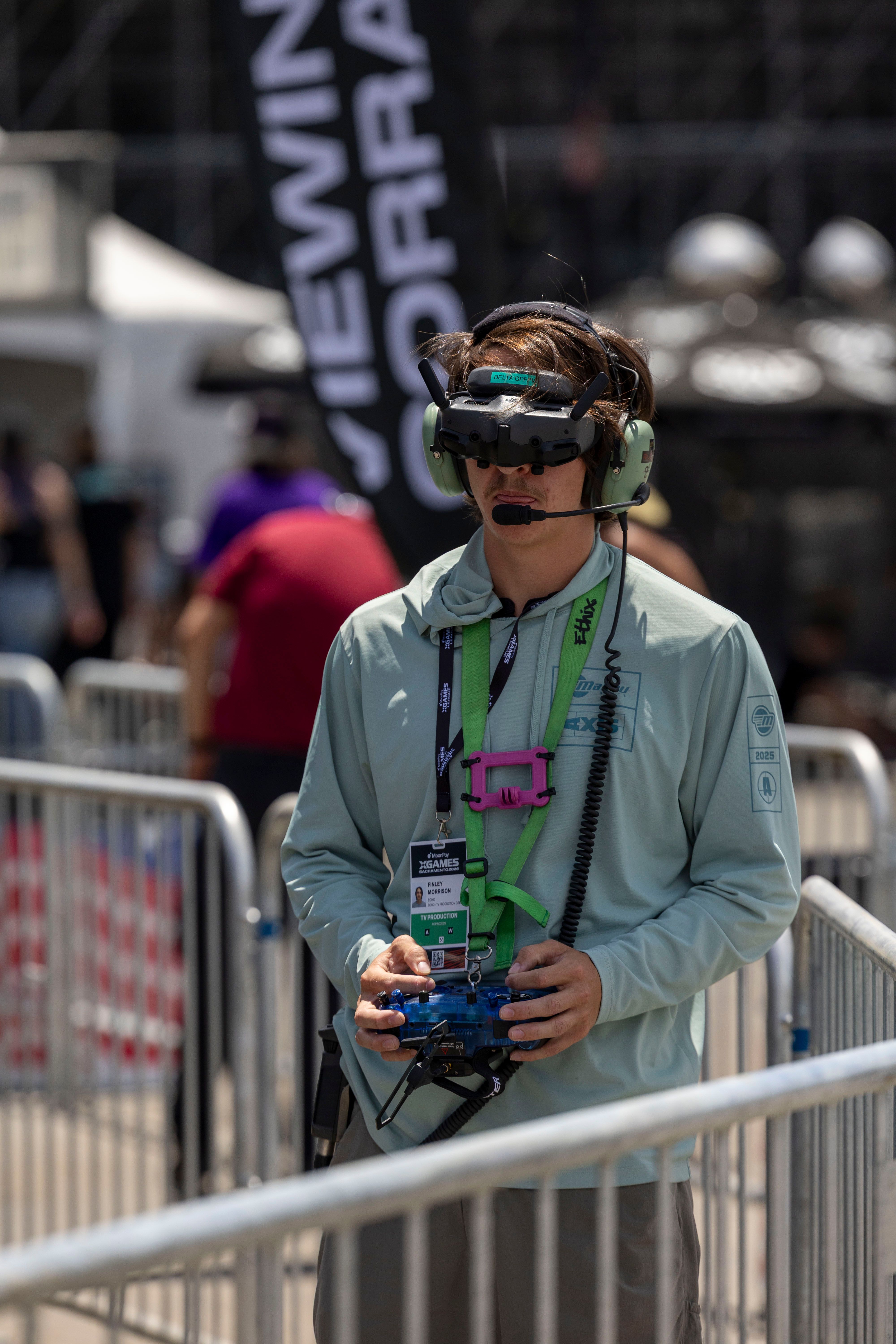 Drone racing pilot uses VR goggles and controller during competition outdoors. Focused and concentrated.