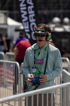Drone racing pilot uses VR goggles and controller during competition outdoors. Focused and concentrated.