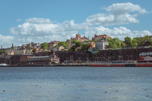 Free A picturesque view of Stockholm's waterfront with historic buildings under a bright blue sky. Stock Photo