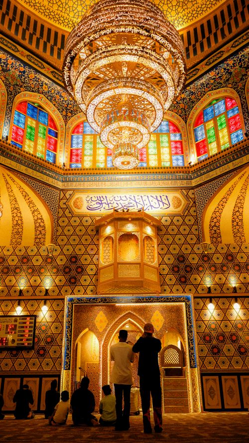 Free Stunning mosque interior featuring intricate patterns and colorful stained glass with a large chandelier. Stock Photo