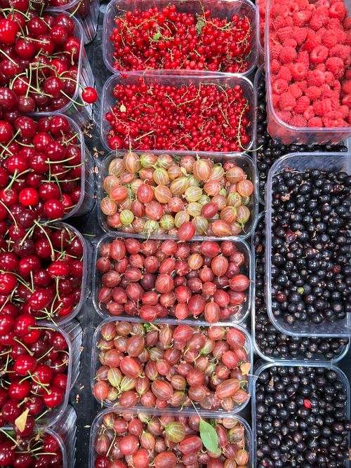 Free Top view of various summer berries including raspberries, cherries, and gooseberries in containers. Stock Photo