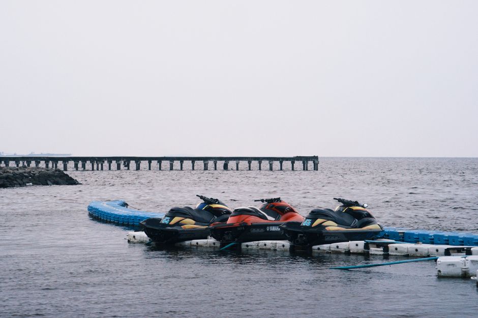 Jet skis docked on a calm day at Jakarta's coastal marina, Indonesia, under an overcast sky.