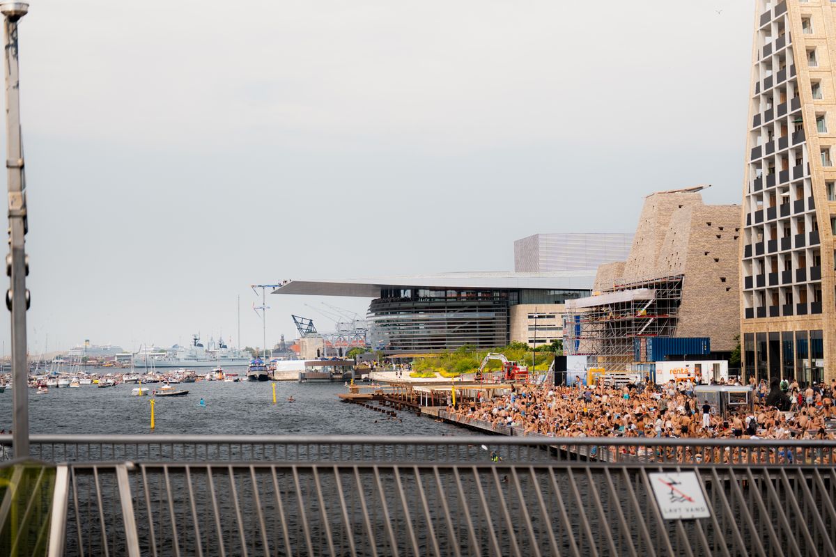 Multime asezata pe treptele unui port urban, vara, cu arhitectura moderna