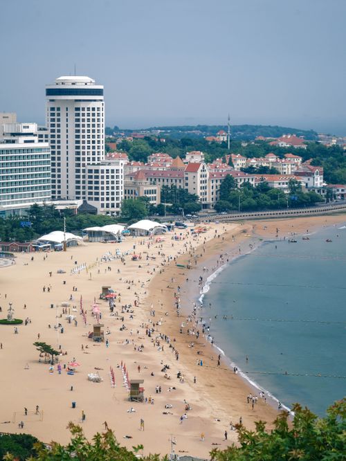Free A vibrant summer day at a bustling beachfront with people enjoying the sun, sea, and city views. Stock Photo