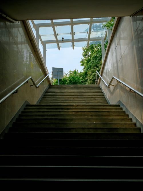 Free Staircase ascending to a bright, tree-lined exit with natural lighting. Stock Photo