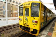 A vibrant yellow Y-DC125 train at Nishi-Karatsu Station in Saga, Japan.