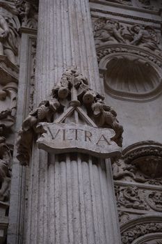 Intricately carved architectural column featuring a prominent 'ULTRA' inscription in classical style.