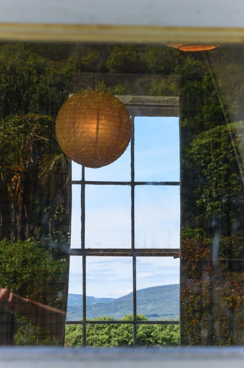Free Reflection of a paper lantern and scenic view through a window in Bantry, Ireland. Stock Photo