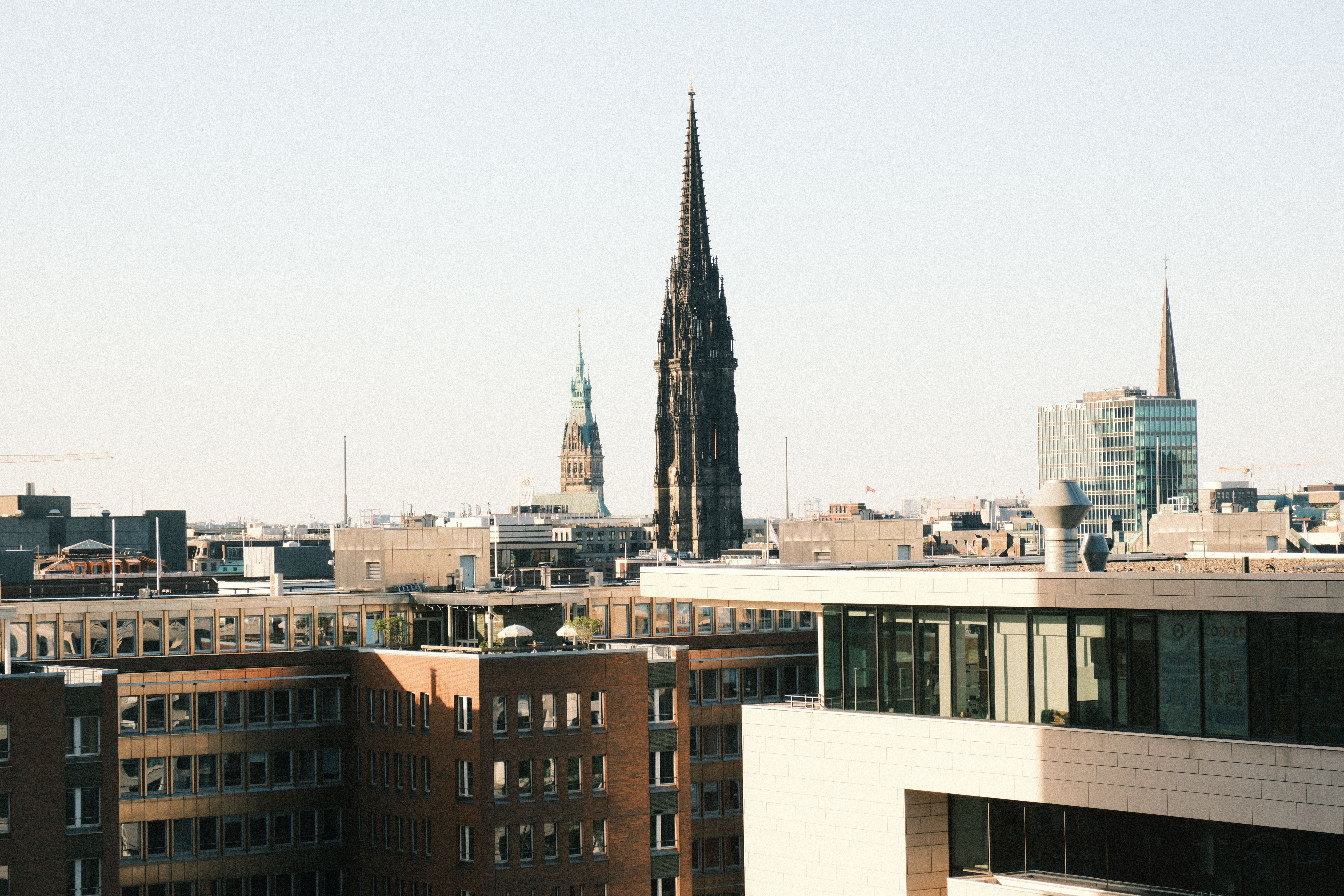A panoramic view of Hamburg with prominent church spires under a clear sky, showcasing urban architecture.