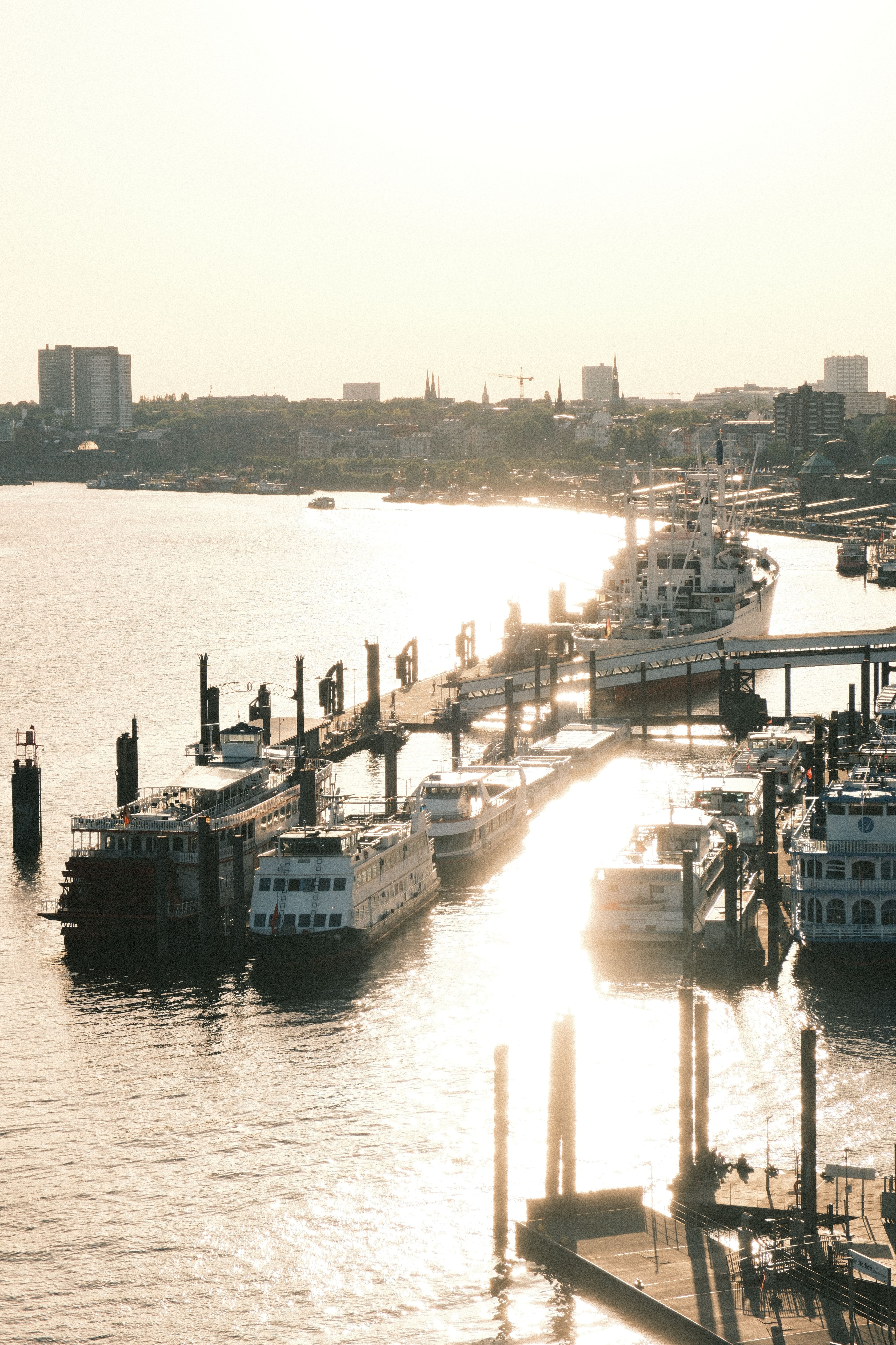 A tranquil view of Hamburg Harbor with boats docked, bathed in sunset light.