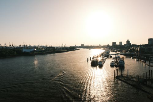 Free A stunning sunset view of the harbor in Hamburg, Germany, featuring boats and city skyline. Stock Photo