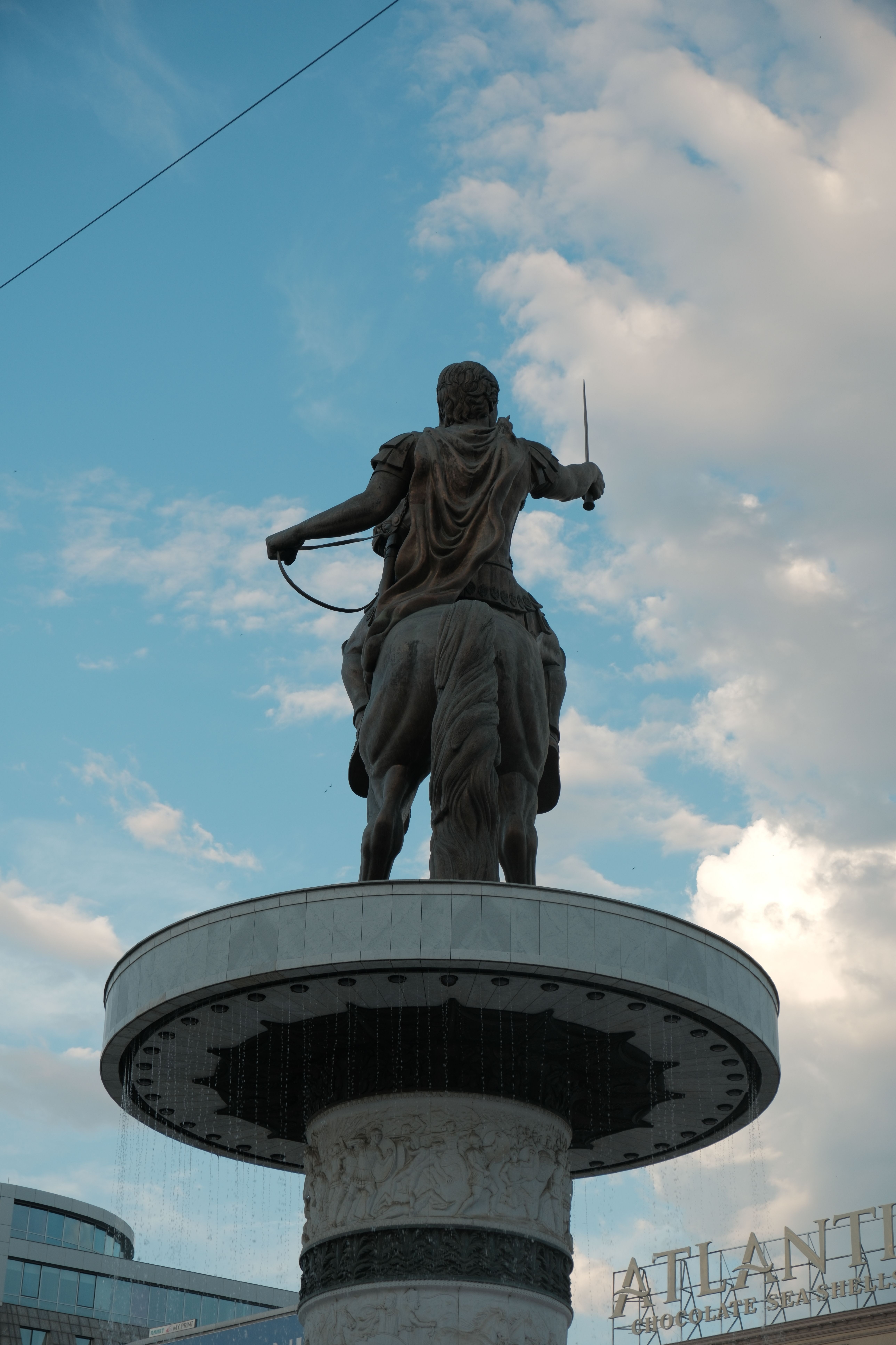 The statue in Skopje, North Macedonia, depicting a warrior on horseback against a blue sky.