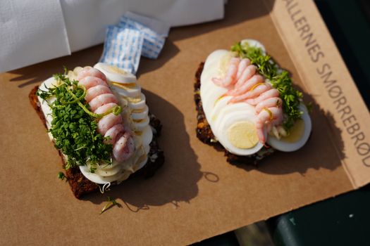 Traditional Danish smørrebrød with shrimp, eggs, and herbs on rye bread in Copenhagen.