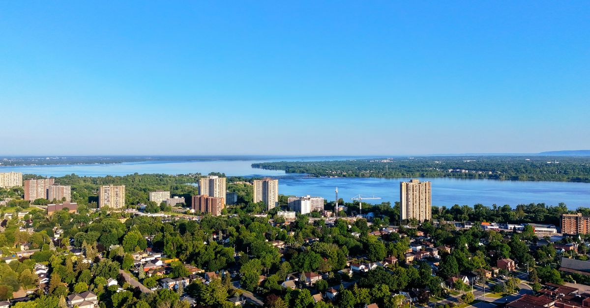 Aerial view of a cityscape with lake and skyline under a clear blue sky.