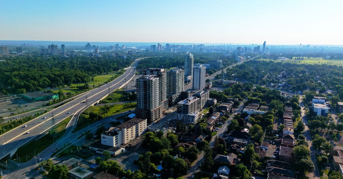 Aerial view of a cityscape featuring highways, residential areas, and skyscrapers at day.