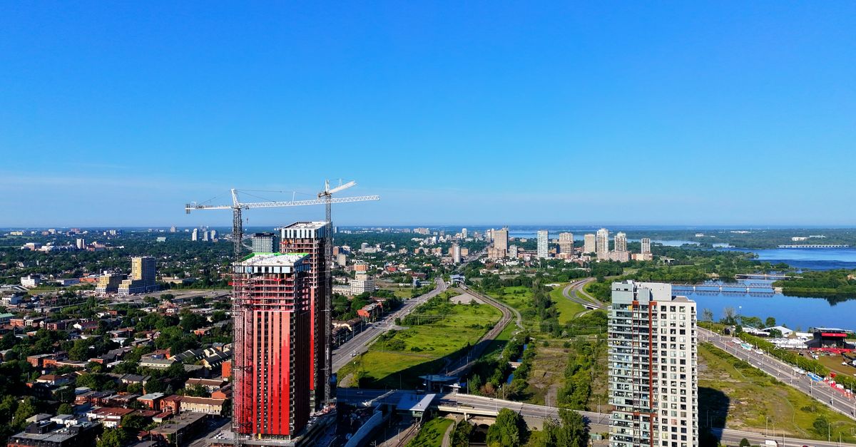 Aerial view of a cityscape with construction and skyline under a clear blue sky.