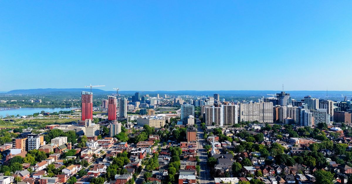 Aerial view of Montreal skyline with tall buildings and blue sky, showcasing urban architecture.
