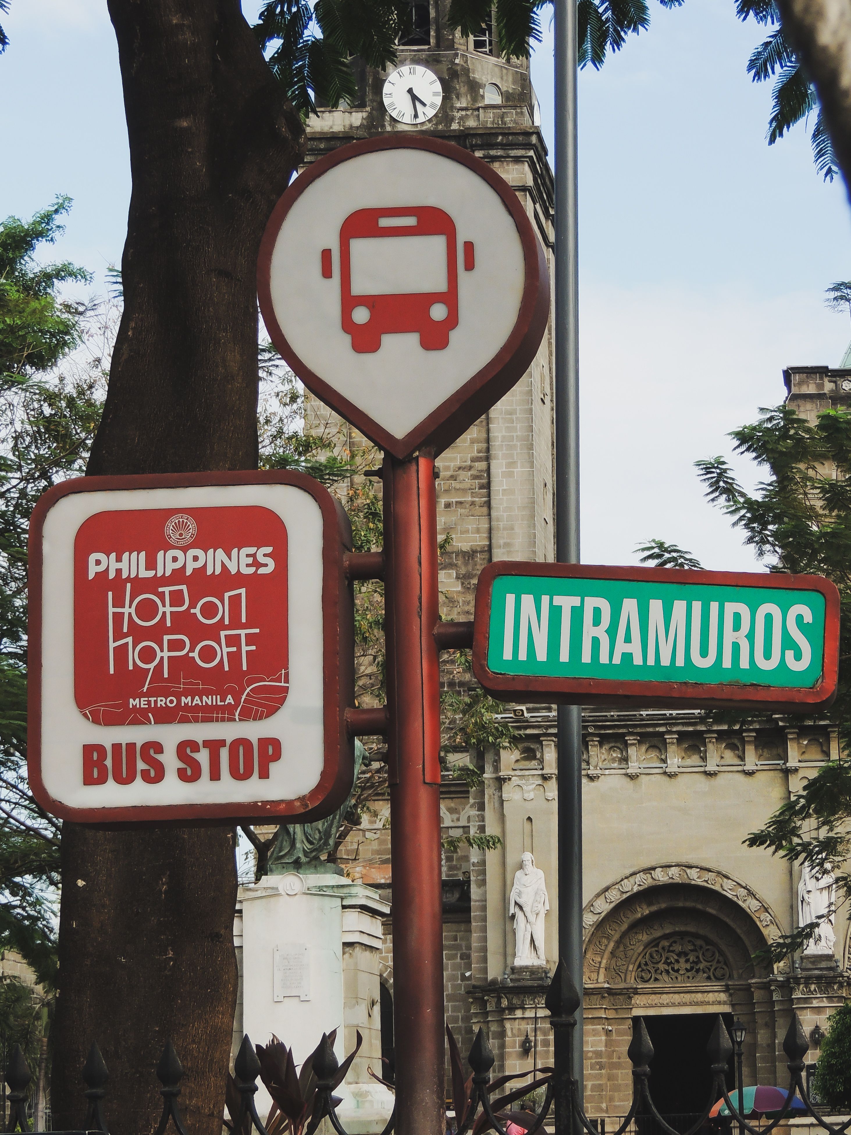 Bus stop sign in Intramuros, Manila featuring hop-on hop-off service signage.