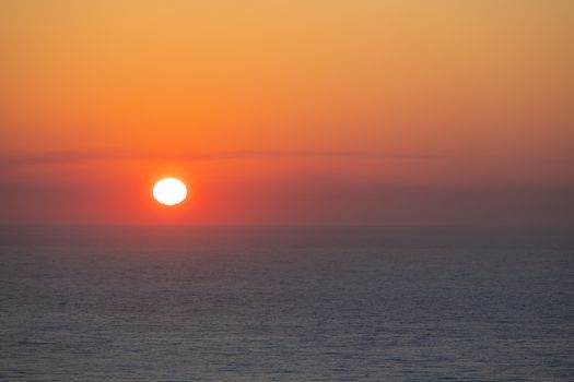 Capture of a breathtaking sunset over the ocean with vibrant hues of orange and red.