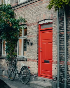 Brick building facade with a red door and bicycle in Copenhagen, Denmark.
