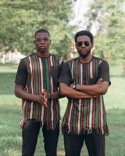 Free Two men in striped traditional African clothing standing in a park setting. Stock Photo