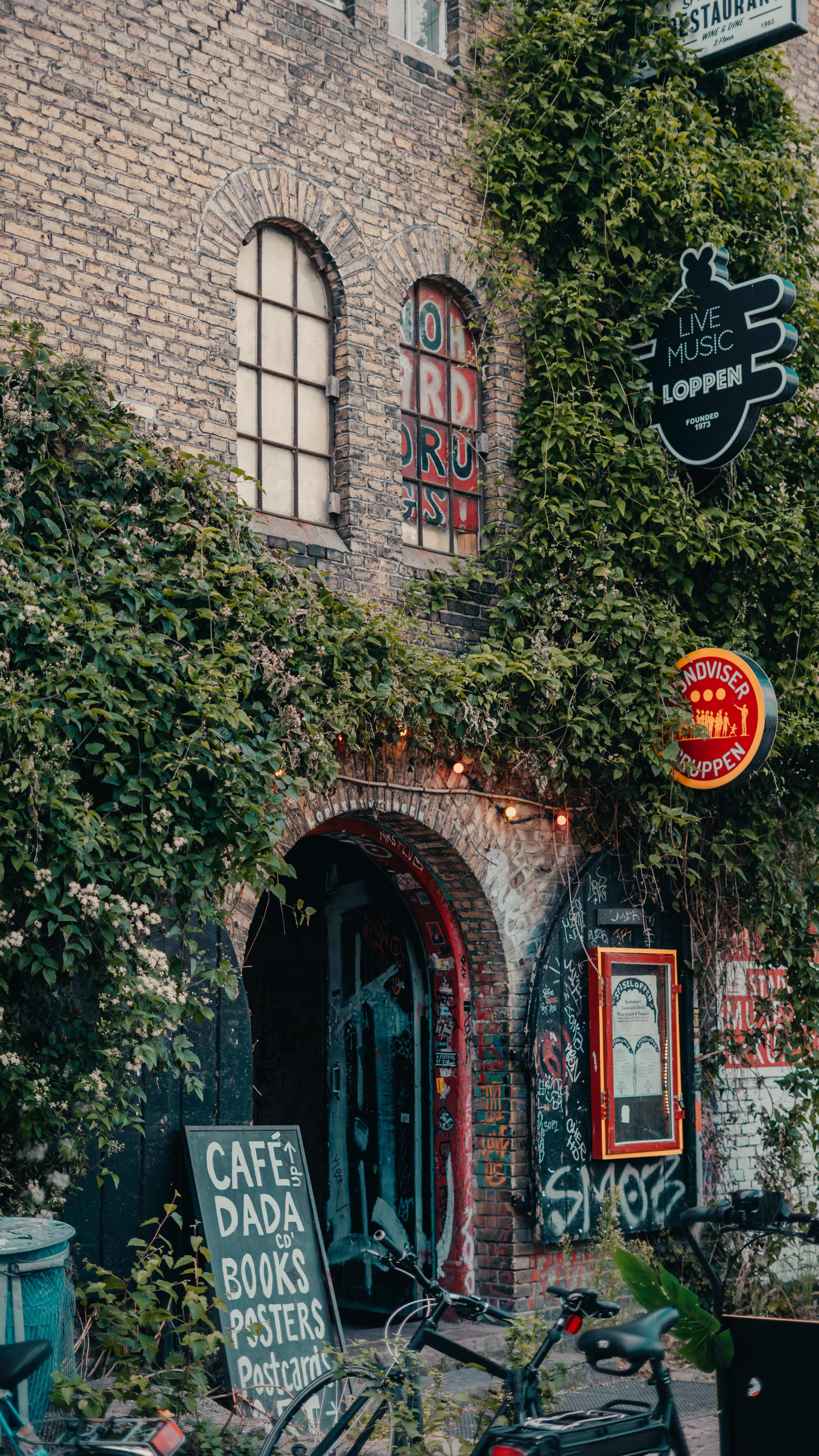 A lively street corner in Christiania, Kopenhaga, showcasing a cultural hub with graffiti and vibrant signage.