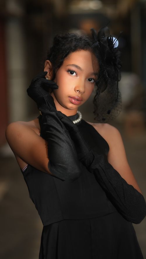 Free Chic portrait of a young woman wearing a black dress and gloves, exuding elegance and style. Stock Photo