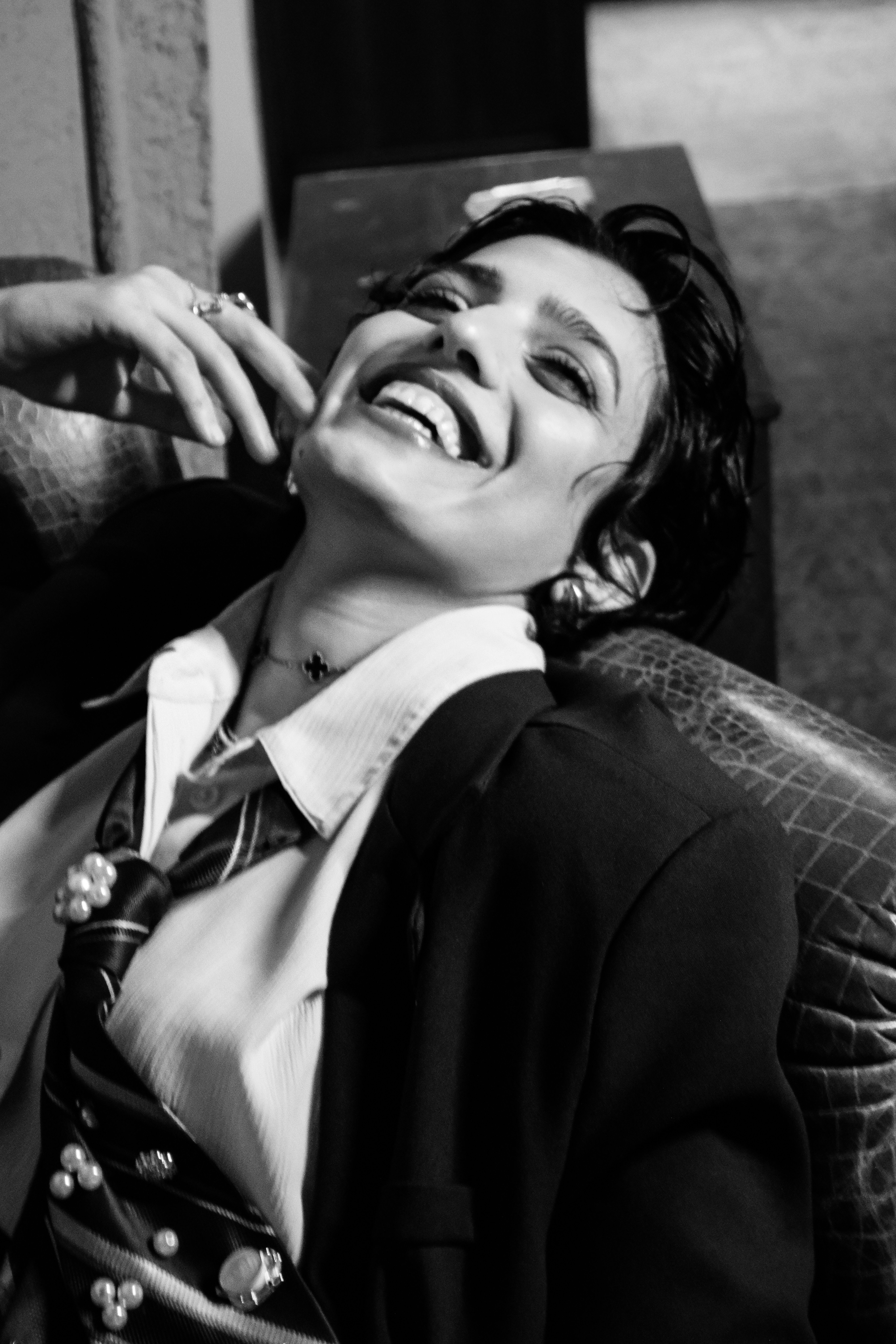 Chic woman in suit laughing with stylish tie. Black and white portrait.