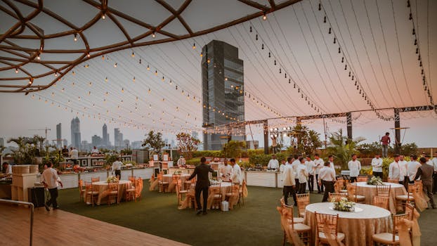 在孟买日落时分的印度天际线下，优雅的屋顶活动布置了桌子和灯光