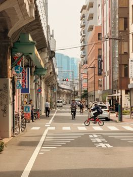 Vibrant Tokyo street scene featuring cyclists and pedestrians on a sunny day.