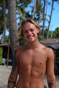 一个光着膀子、开朗的男人，在海滩上纹着身，享受着阳光明媚的一天