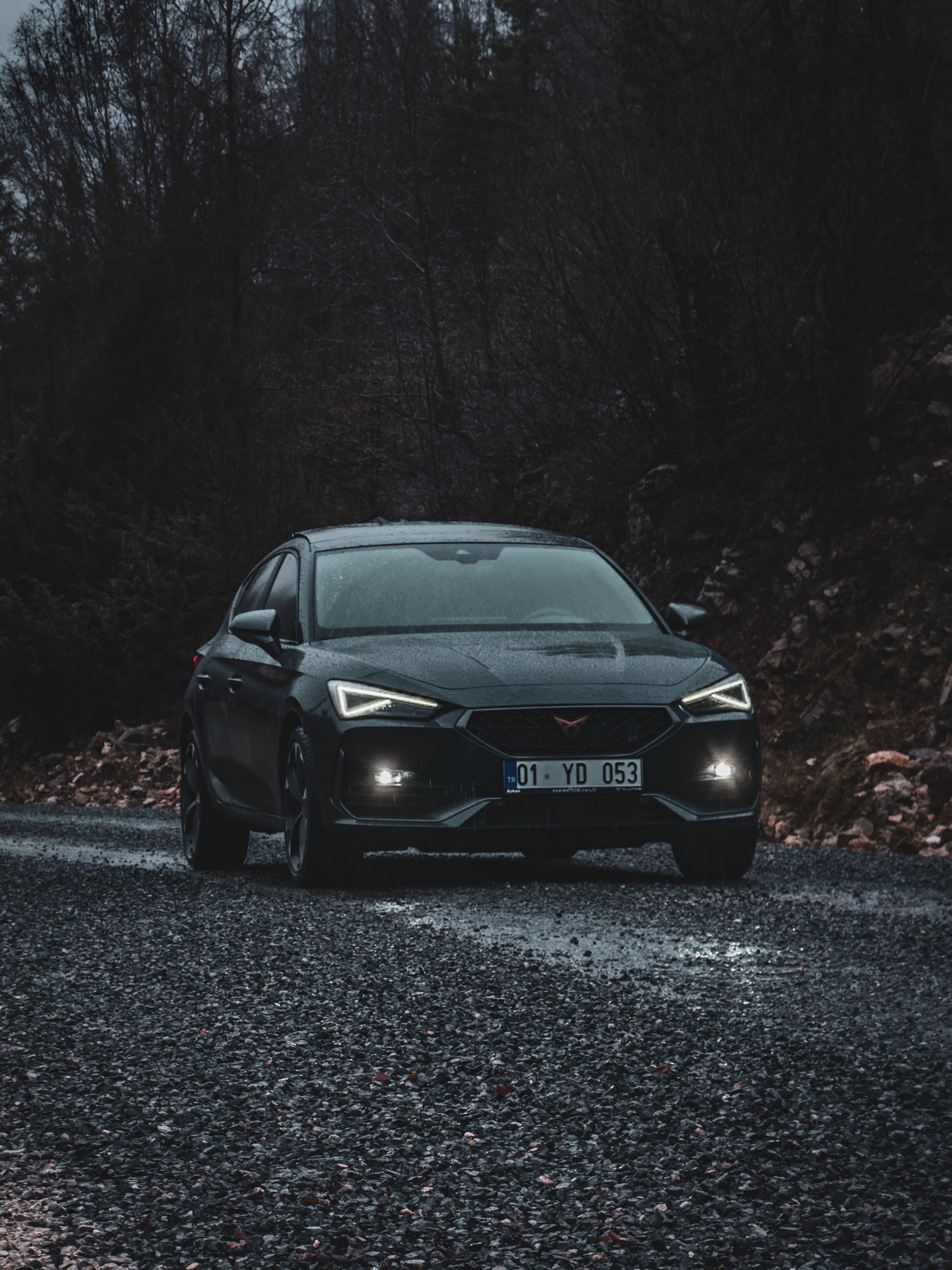 Silver sports coupe on a misty nighttime road with dramatic reflections