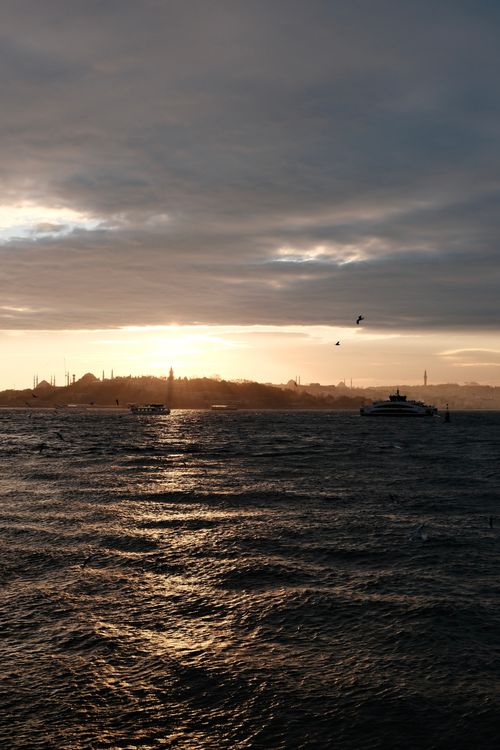 Free A serene sunset view over the Bosphorus Strait in Istanbul, Türkiye with ferries and seagulls. Stock Photo