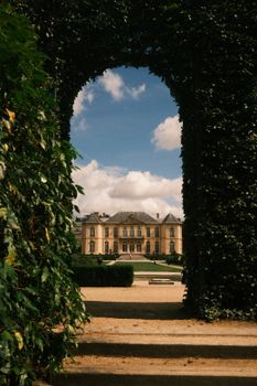 Elegant chateau framed by lush greenery and blue sky, showcasing classic European architecture.