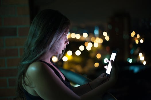 A young woman engaging with her smartphone on a balcony at night, surrounded by city lights.