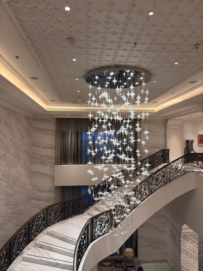 Hotel lobby with a sweeping marble staircase and cascading chandelier — photo by Soham Kundu on Pexels