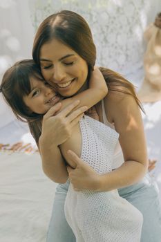 Warm embrace of a mother and daughter in a sunny outdoor setting, full of love and joy.