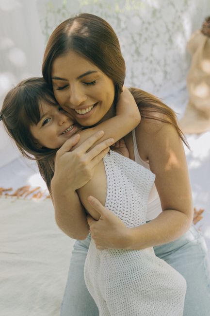 Warm embrace of a mother and daughter in a sunny outdoor setting, full of love and joy.