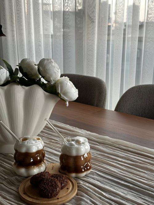 Free Stylish indoor scene with coffee, pastry, and floral decor. Perfect for lifestyle and home design themes. Stock Photo