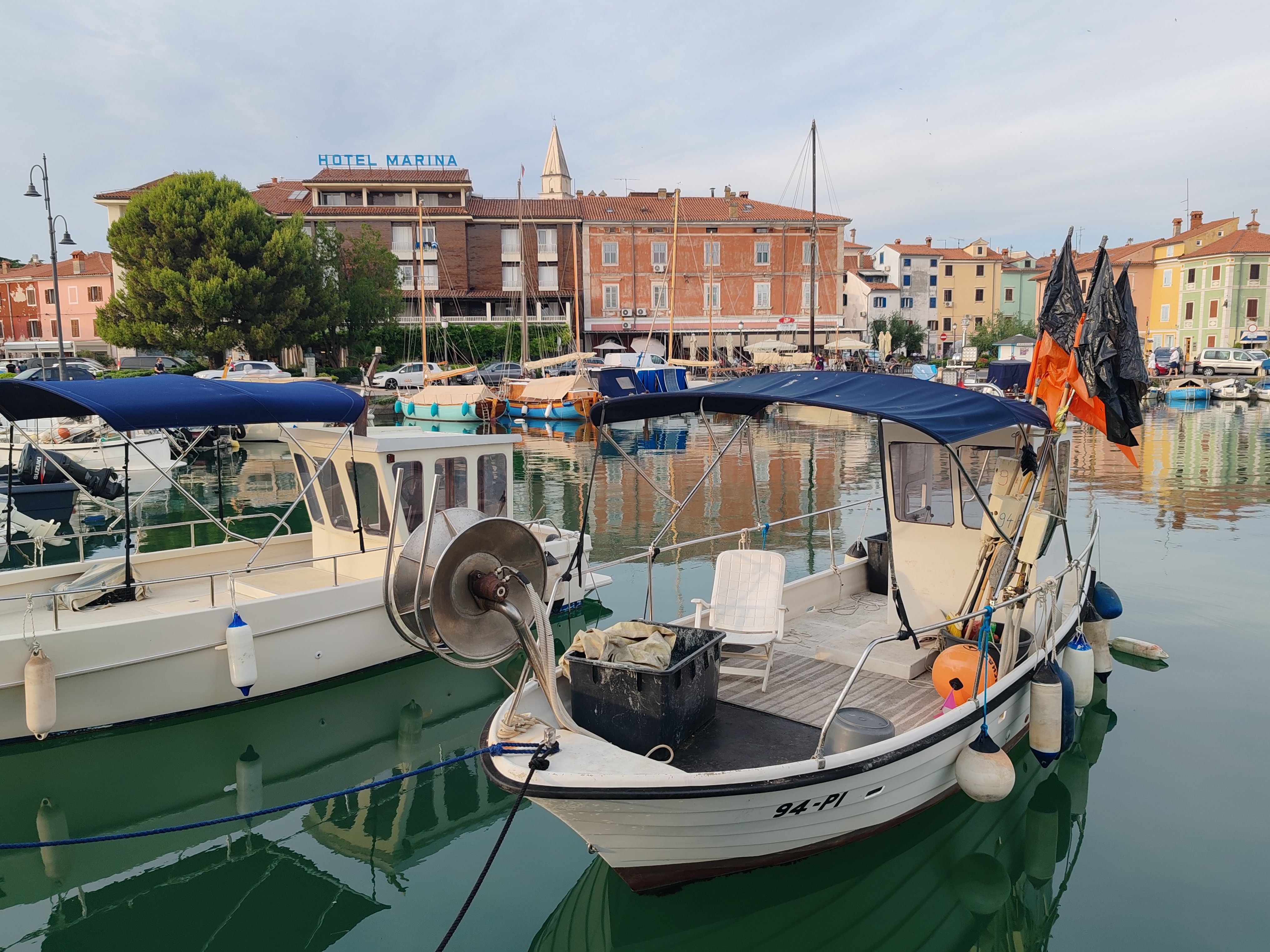 Scenic view of a marina with fishing boats docked by colorful European buildings.