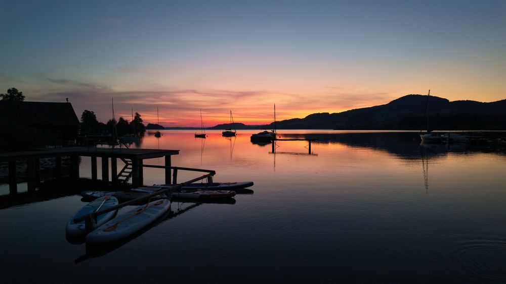 Lacul Wolfgangsee la apus, cu apa perfect calmă și munții reflectați